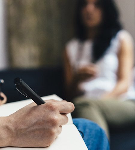 A clinician takes notes while meeting with an individual with lived experience.